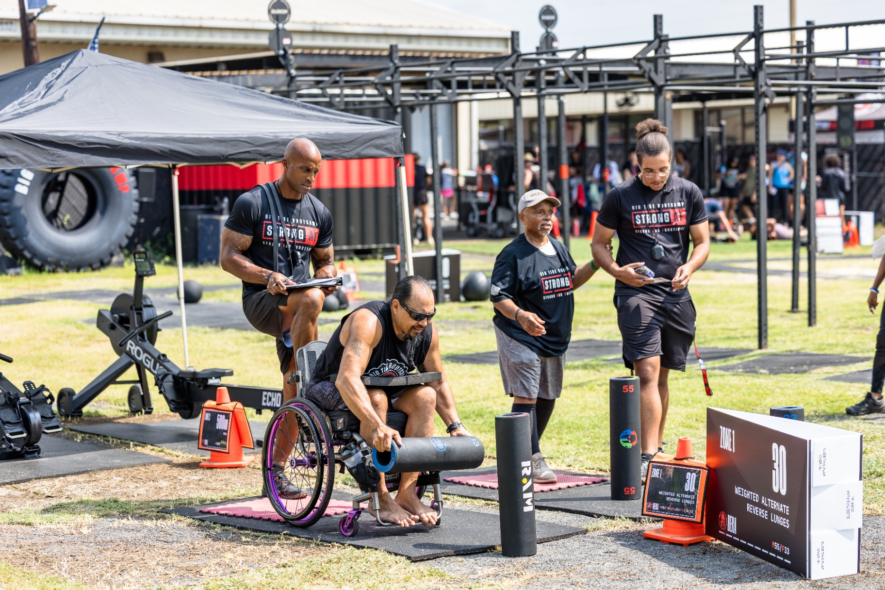 Adaptive athlete in a wheelchair training Spartan DEKA alongside Big Tire Bootcamp coaches on Warrior Field, Ewa Beach